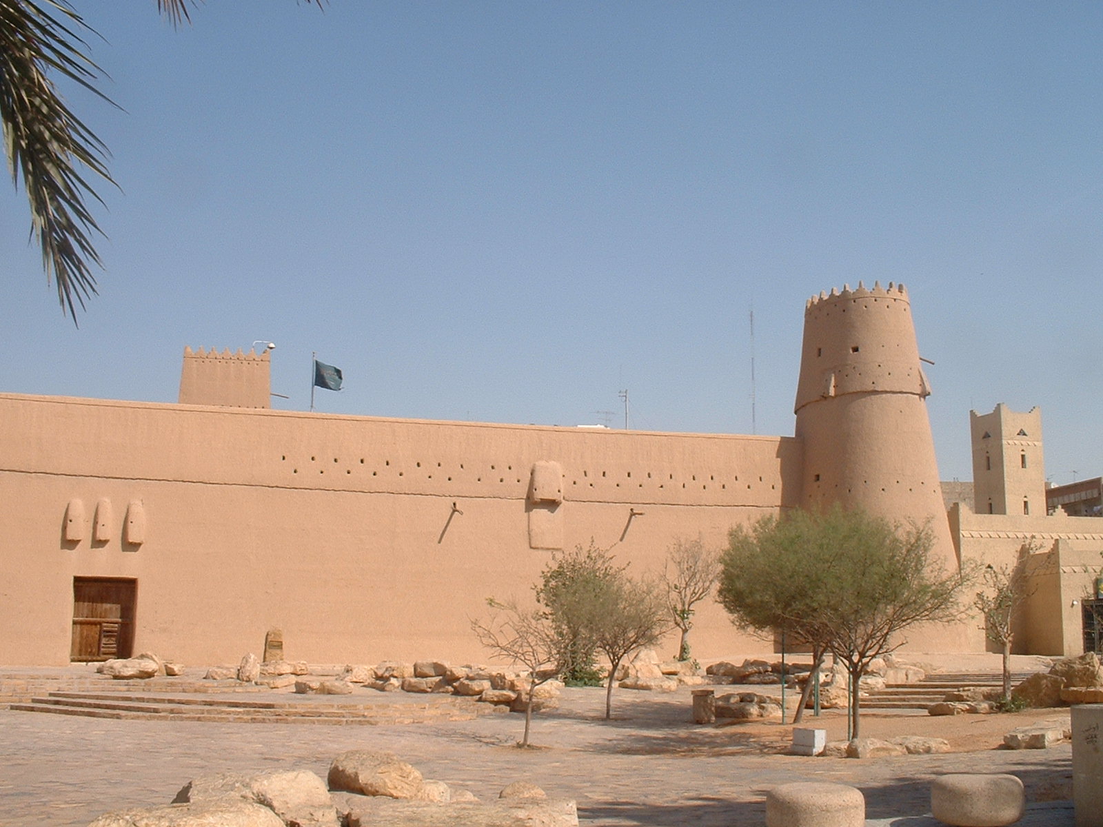 قصر المصمك الذي ارتبط باسترداد الرياض سنة ١٩٠٢م؛ نقطة البداية التي يعود إليها كل حديث عن التوحيد. المصدر: «قصر المصمك في الرياض» — تصوير Baptiste Marcel، 2006م، Wikimedia Commons، ملكية عامة · https://commons.wikimedia.org/wiki/File%3AMasmak_castle.jpg